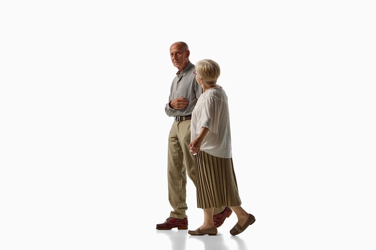 Senior couple walking together and talking isolated on white background. Concept of healthy aging, everyday mobility, supportive partnership.